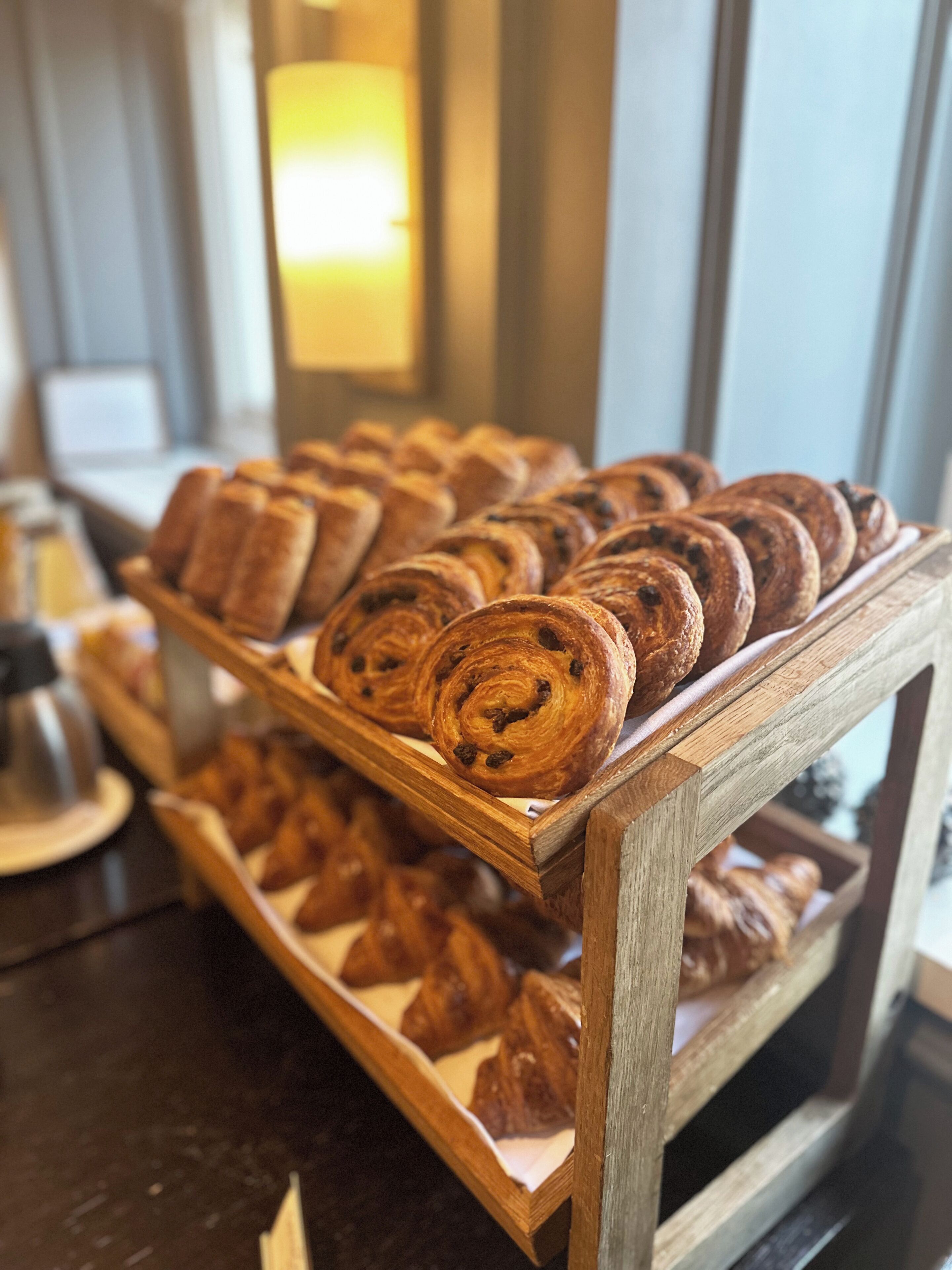 A wooden display case with various pastries and bread.