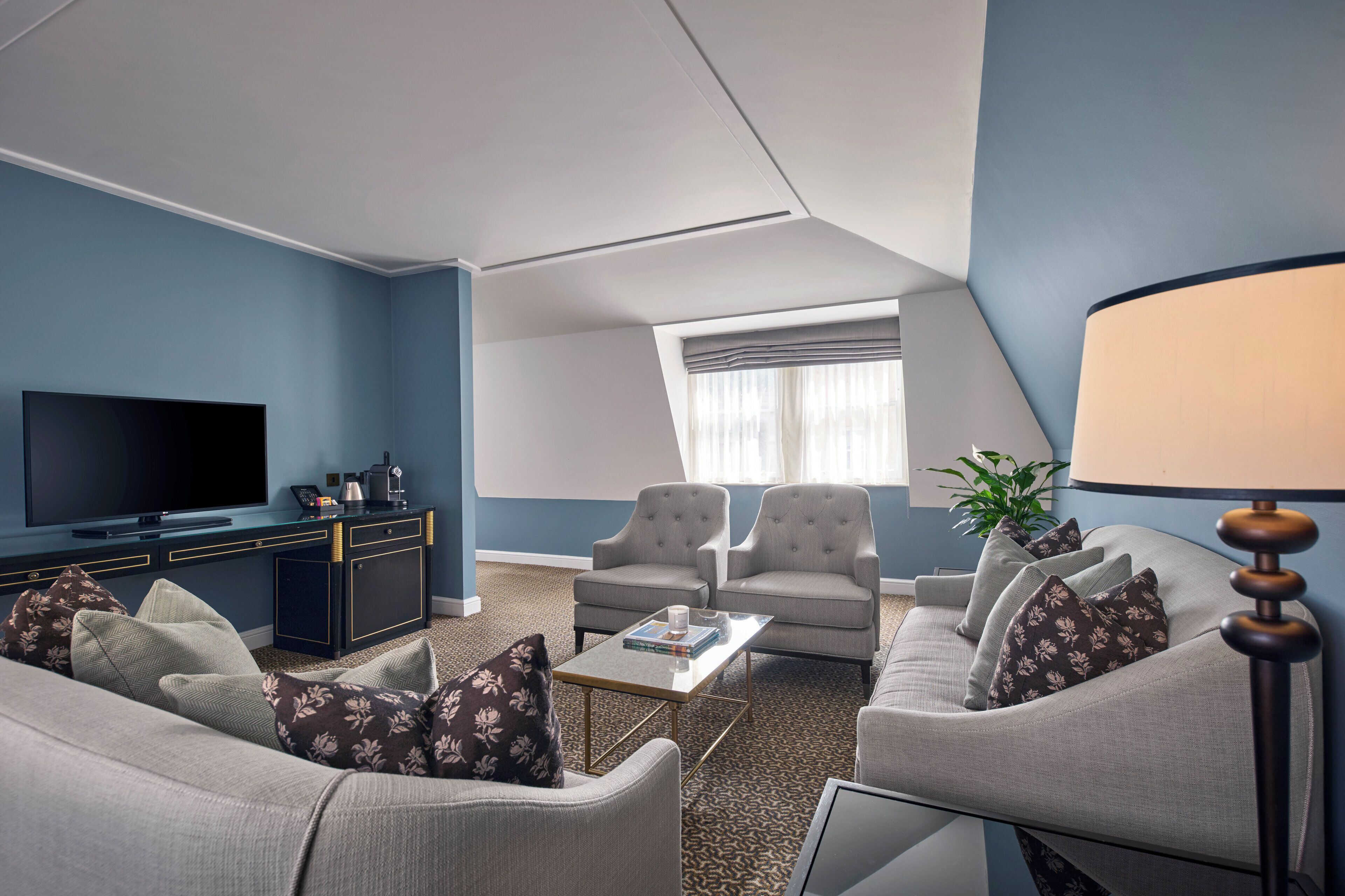 A modern living room with a flat-screen TV, two armchairs, a sofa, and a coffee table.
