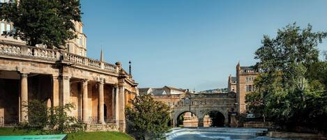 A historic building with classical architecture, a bridge, and a river.