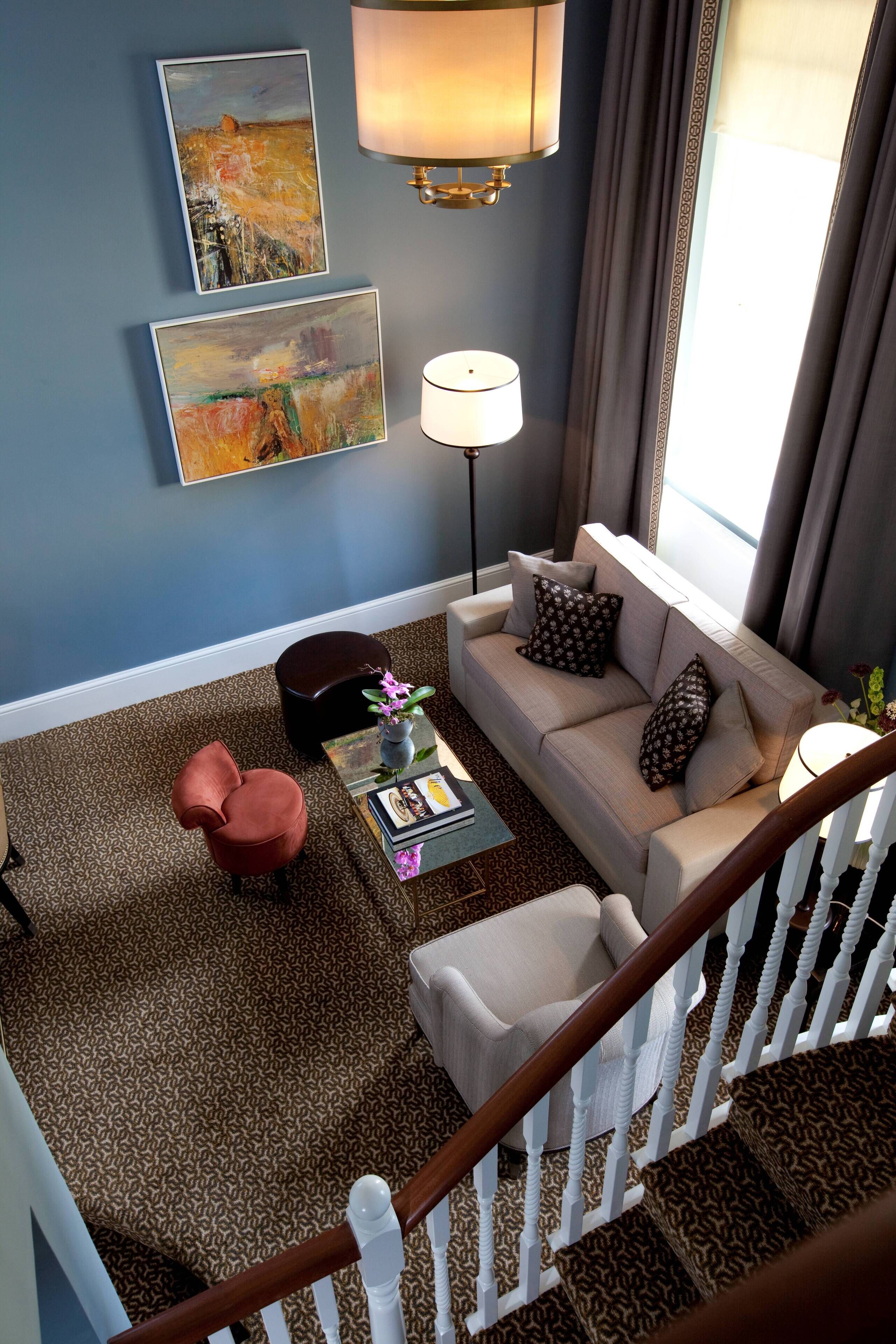 A living room with a sofa, armchair, coffee table, and artwork on the wall.