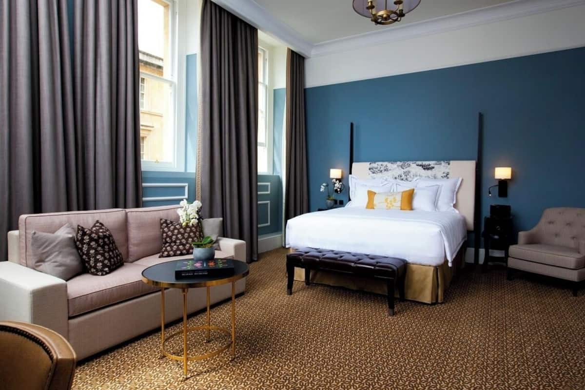 Ein Hotelzimmer mit einem großen Bett, einer Schlafcouch, einem kleinen Tisch und einem Sessel.