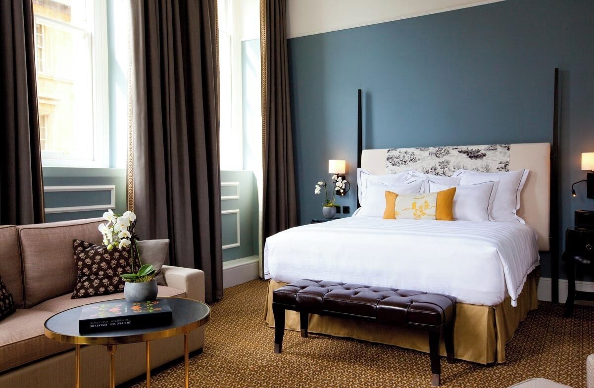 Ein Hotelzimmer mit einem großen Bett, einem Sofa, einem Couchtisch und Blick auf die Stadt.