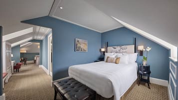 A hotel room with a large bed, a bench, a nightstand, and a desk with a chair.