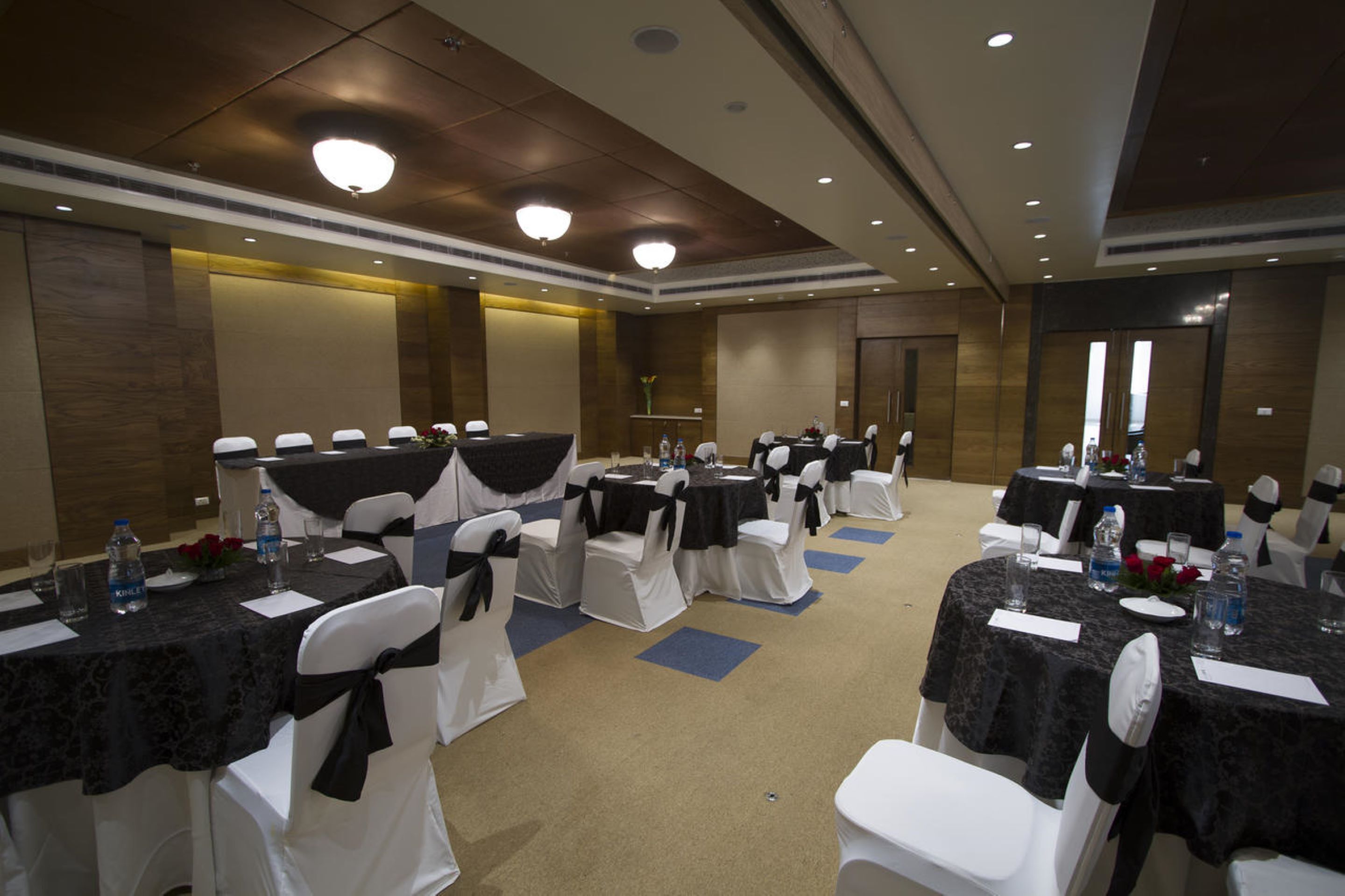 A conference room with multiple tables and chairs, each with a black tablecloth and white chairs.