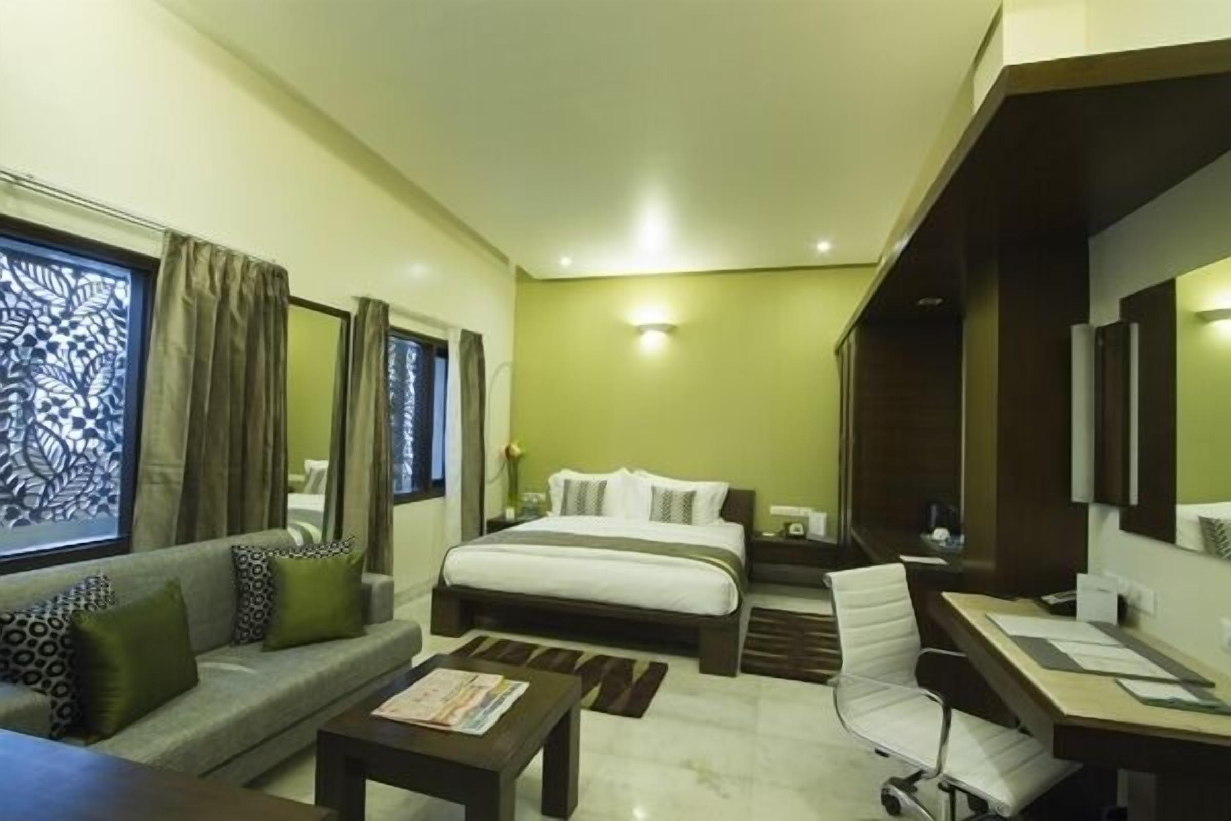 Quarto de hotel com cama, sofá, escrivaninha e cadeira.