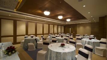 A banquet hall with round tables, white chairs, and blue tablecloths.