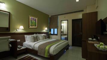 A hotel room with a bed, bedside tables, a desk with a chair, a mirror, and a window with curtains.