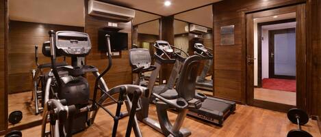 A gym with cardio machines, weightlifting equipment, and a mirror.