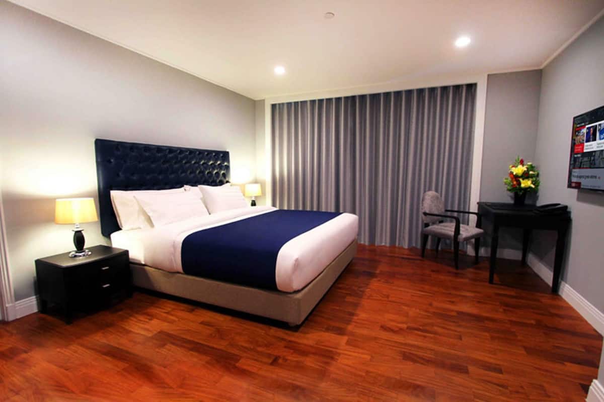 A hotel room with a large bed, a nightstand, a desk, and a chair.