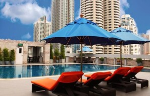A poolside area with lounge chairs and umbrellas, a pool, and high-rise buildings in the background. - Gm Complex (Bangkok)