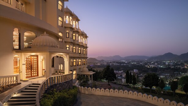 Un edificio de varios pisos con una entrada imponente, una escalera que conduce a los pisos superiores y vistas del paisaje circundante.