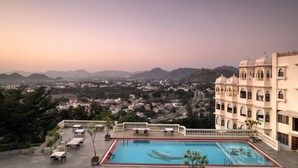 Zona de piscina con vistas a un pueblo y montañas al fondo.
