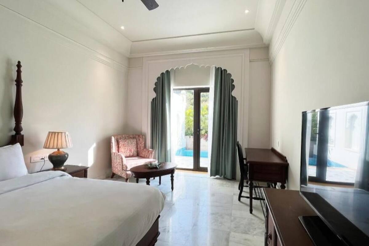 A hotel room with a bed, a desk, a chair, a television, and a view of the outdoors.
