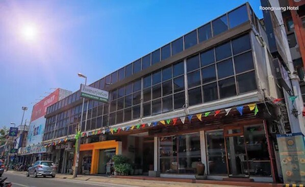 A modern building with large windows and a sign for 'Isuzu Hotel'. - RoongRuang Hotel (Chiang Mai)