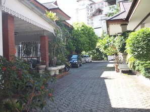 A cobblestone pathway leading to a building with a traditional architectural style, surrounded by lush greenery and potted plants. - RoongRuang Hotel (Chiang Mai)