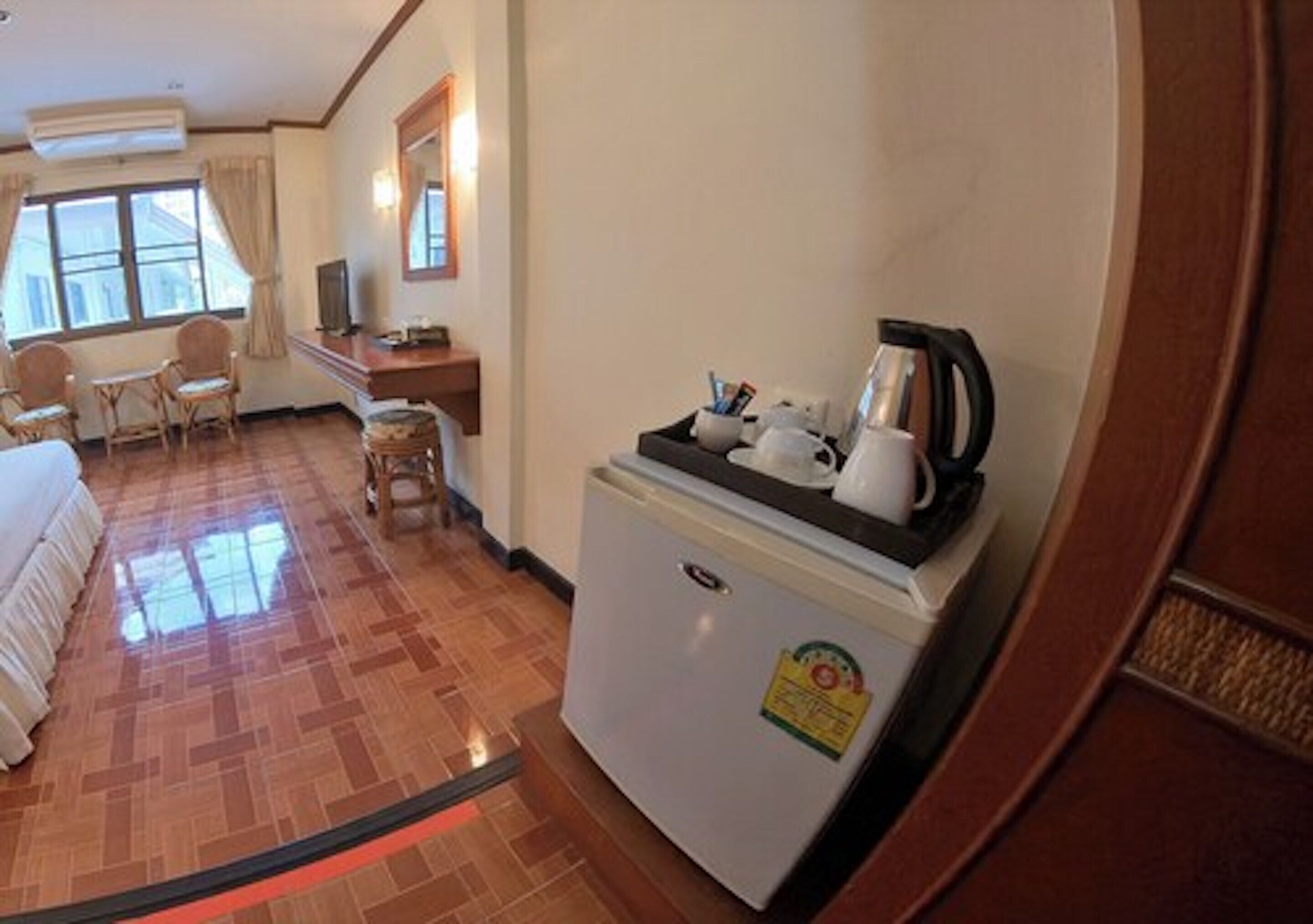 Una habitación de hotel con una cama, una pequeña mesa de comedor, un refrigerador con cafetera y un televisor.