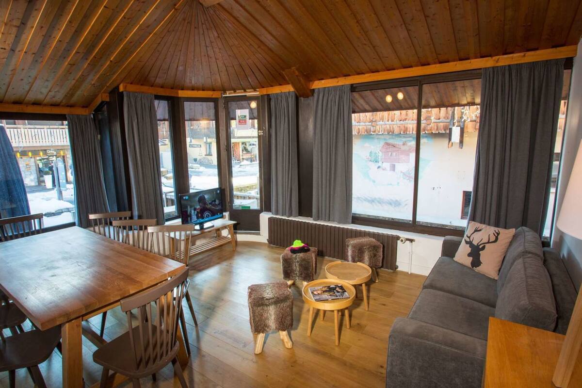 Un intérieur chaleureux avec un plafond en bois, un coin repas avec une table et des chaises, un canapé et une cheminée.
