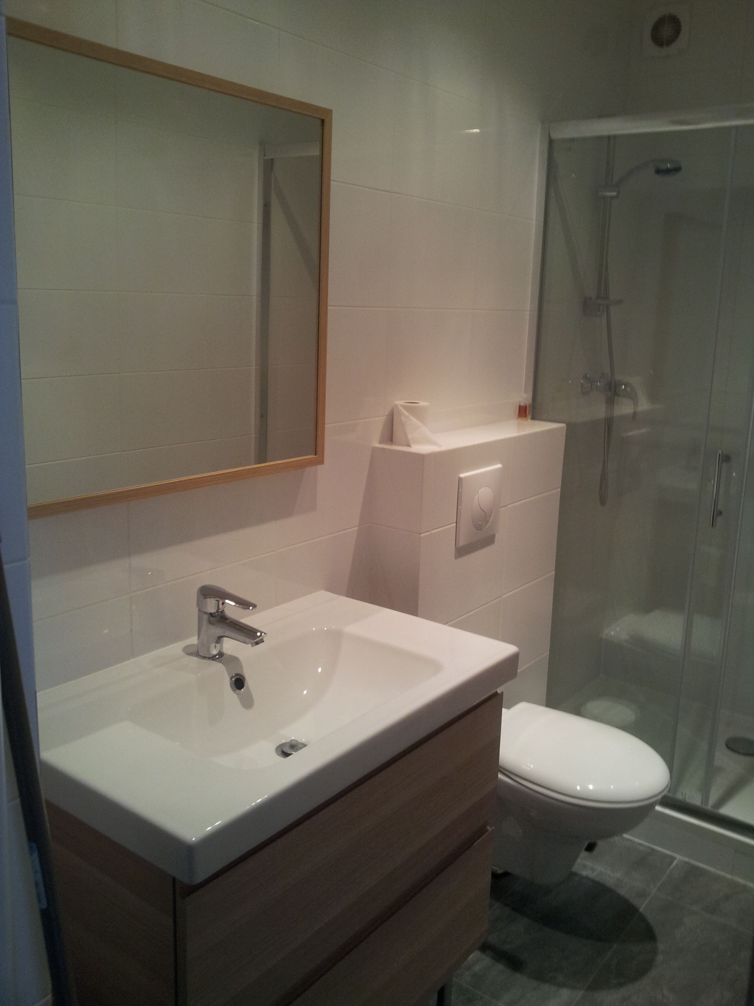 A bathroom with a white sink, mirror, and toilet.