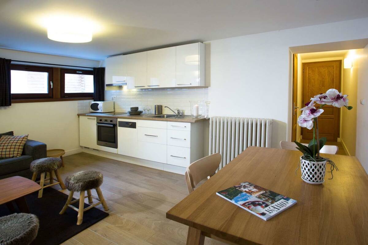 Un espace de vie compact comprenant un coin cuisine, un coin repas et un petit coin salon.