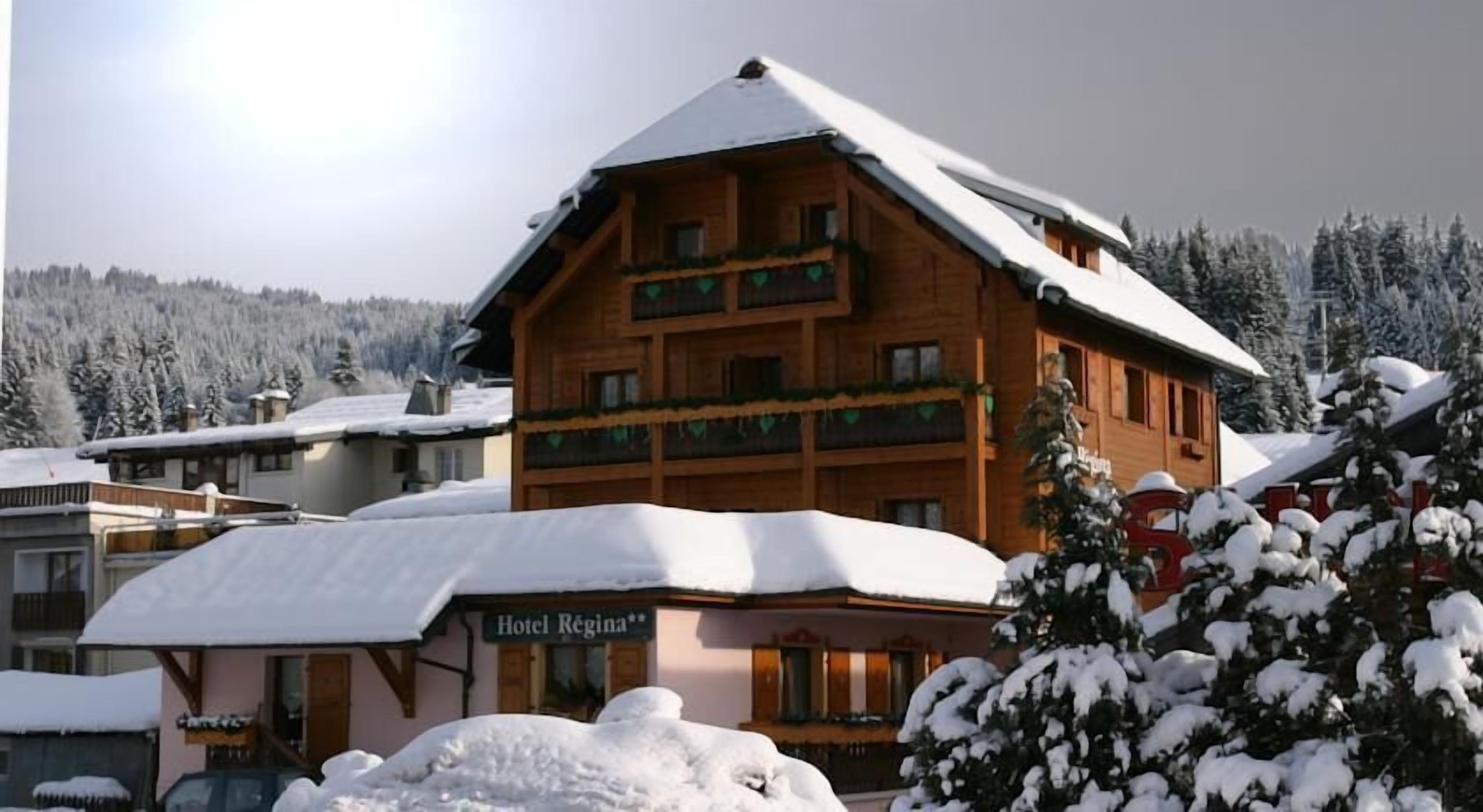 A wooden hotel with a sign reading "Hotel Regina" and balconies with green railings.