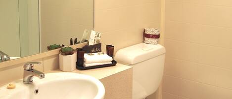 A bathroom with a sink, mirror, toilet, and towel rack.