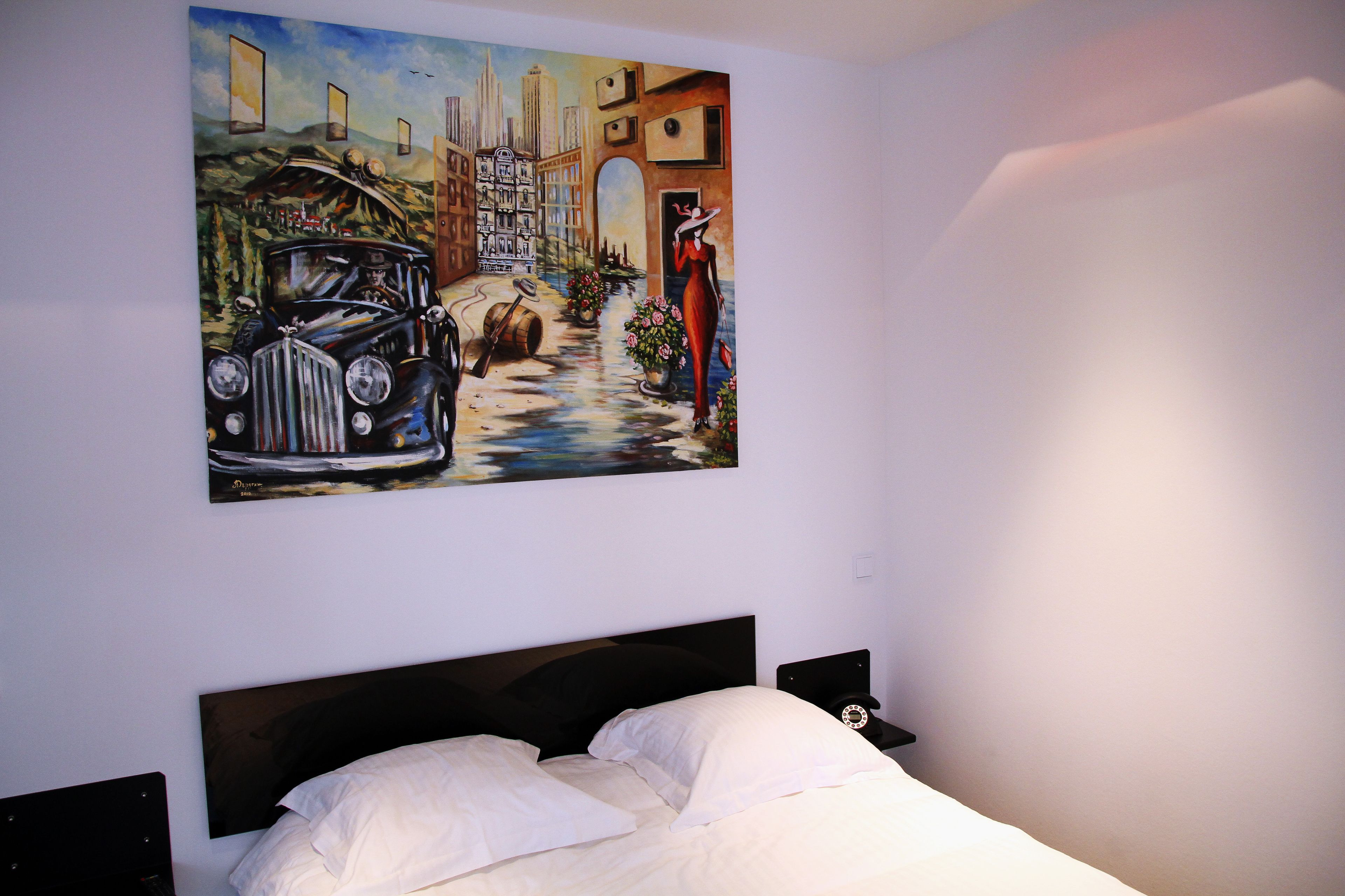 Un dormitorio con cama, mesita de noche y un cuadro en la pared.
