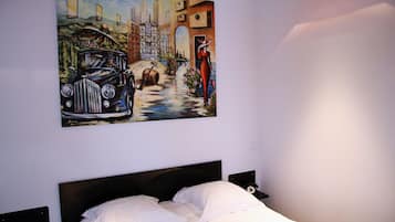 Un dormitorio con cama, mesita de noche y un cuadro en la pared.