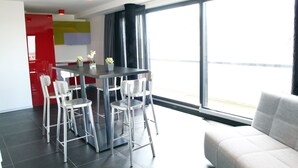 A modern living space with a dining area, a sofa, and a large window offering a view. - Hotel Grey (Luxembourg City)