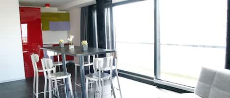 Un espacio de estar moderno con comedor, sofá y un ventanal con vistas.