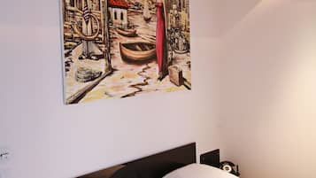 Quarto com cama, mesa de cabeceira e um quadro na parede.