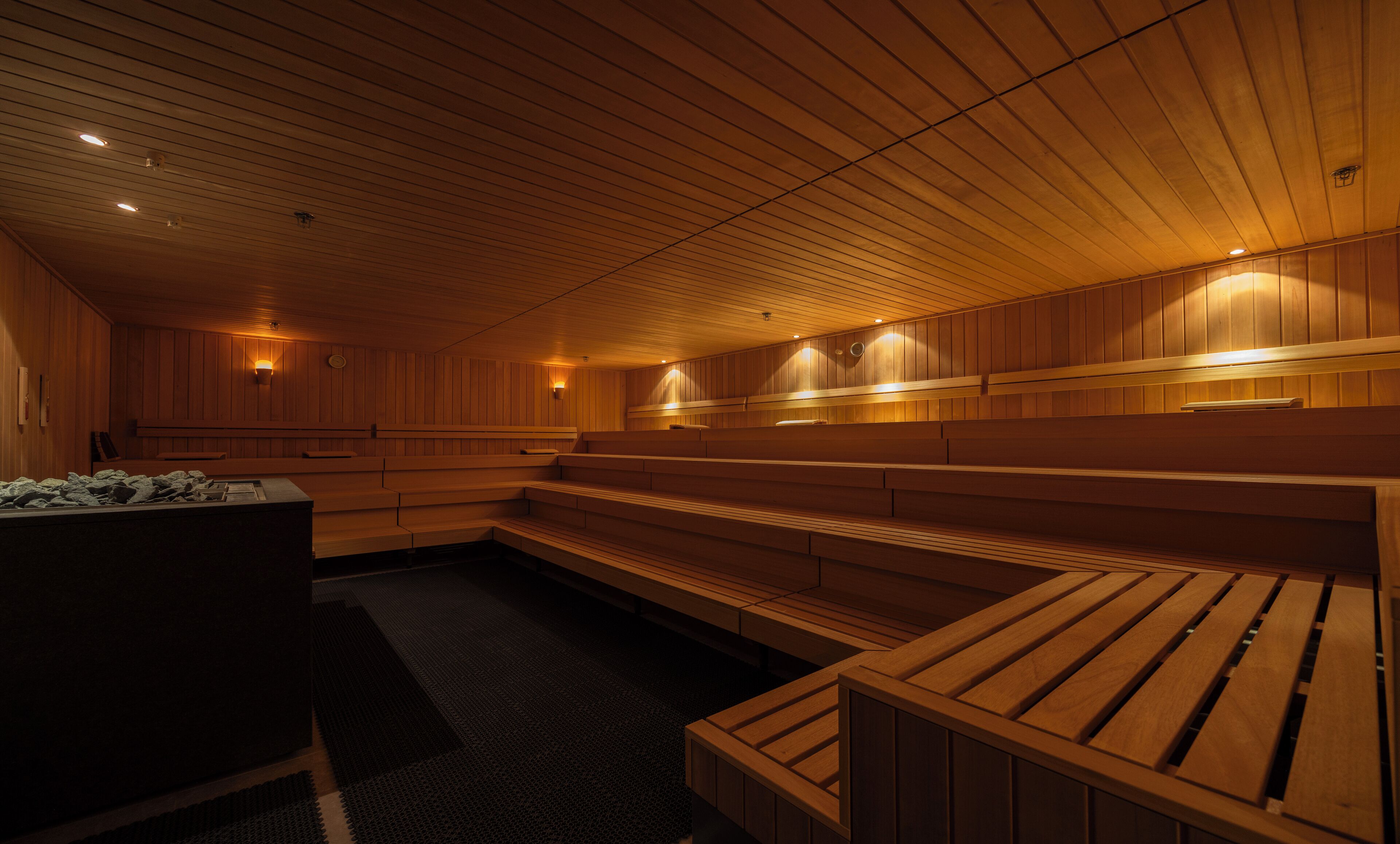 Eine Sauna mit Holzbänken und -wänden, ausgestattet mit Wandleuchten.