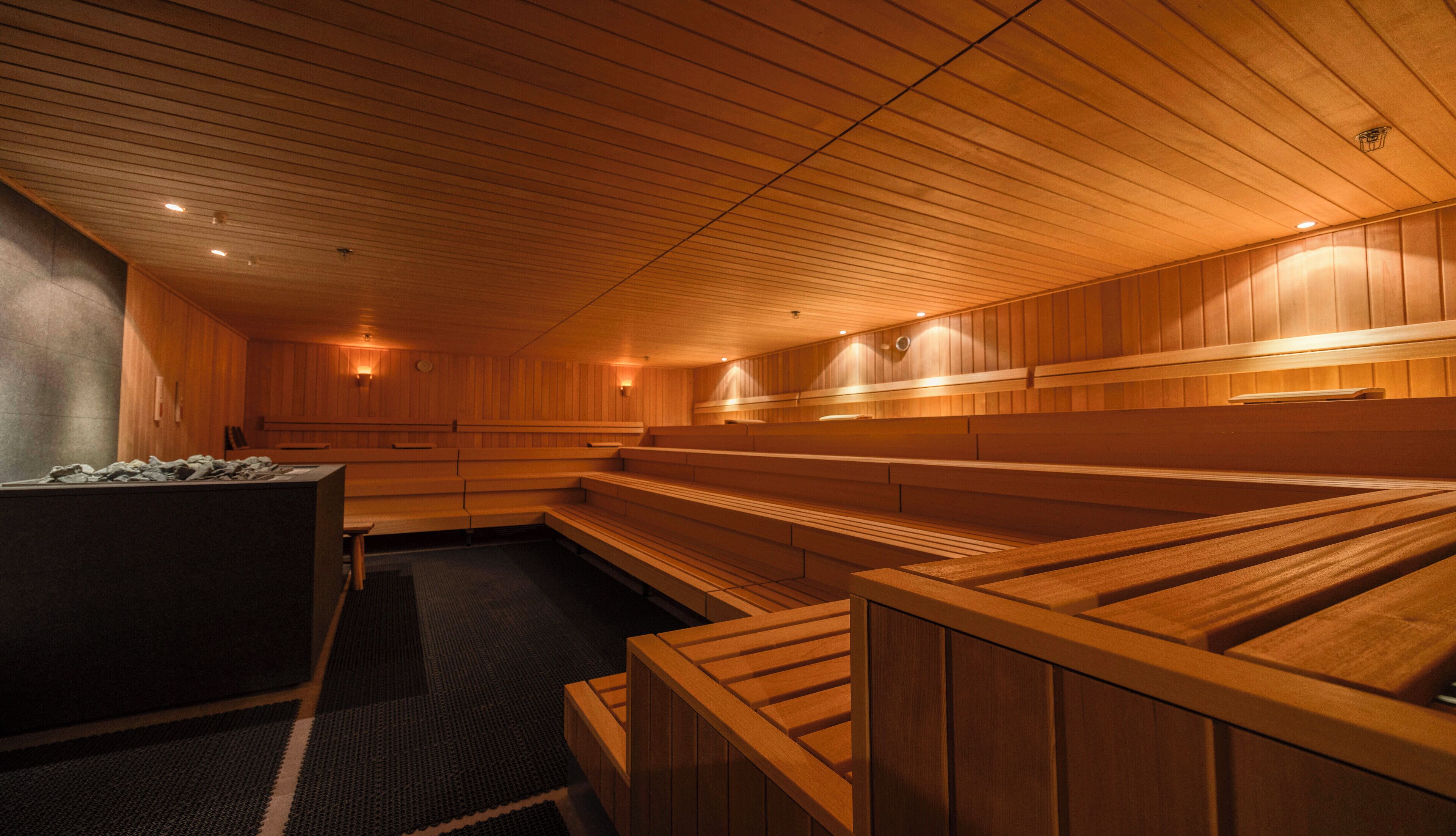 Eine Sauna mit Holzbänken und -wänden, eine Bank mit Handtuch, sowie ein Handtuch auf dem Boden.