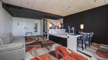 Ein Hotelzimmer mit einem Bett, einem Schreibtisch mit Stuhl, einer Couch und einem gemusterten Teppich.