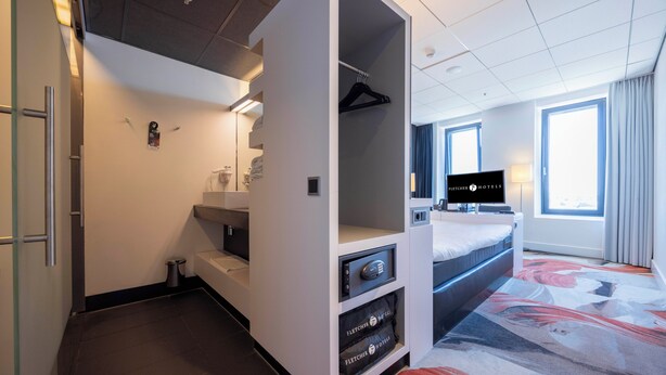 Une chambre d’hôtel avec un lit, une télévision, une armoire et une salle de bain.