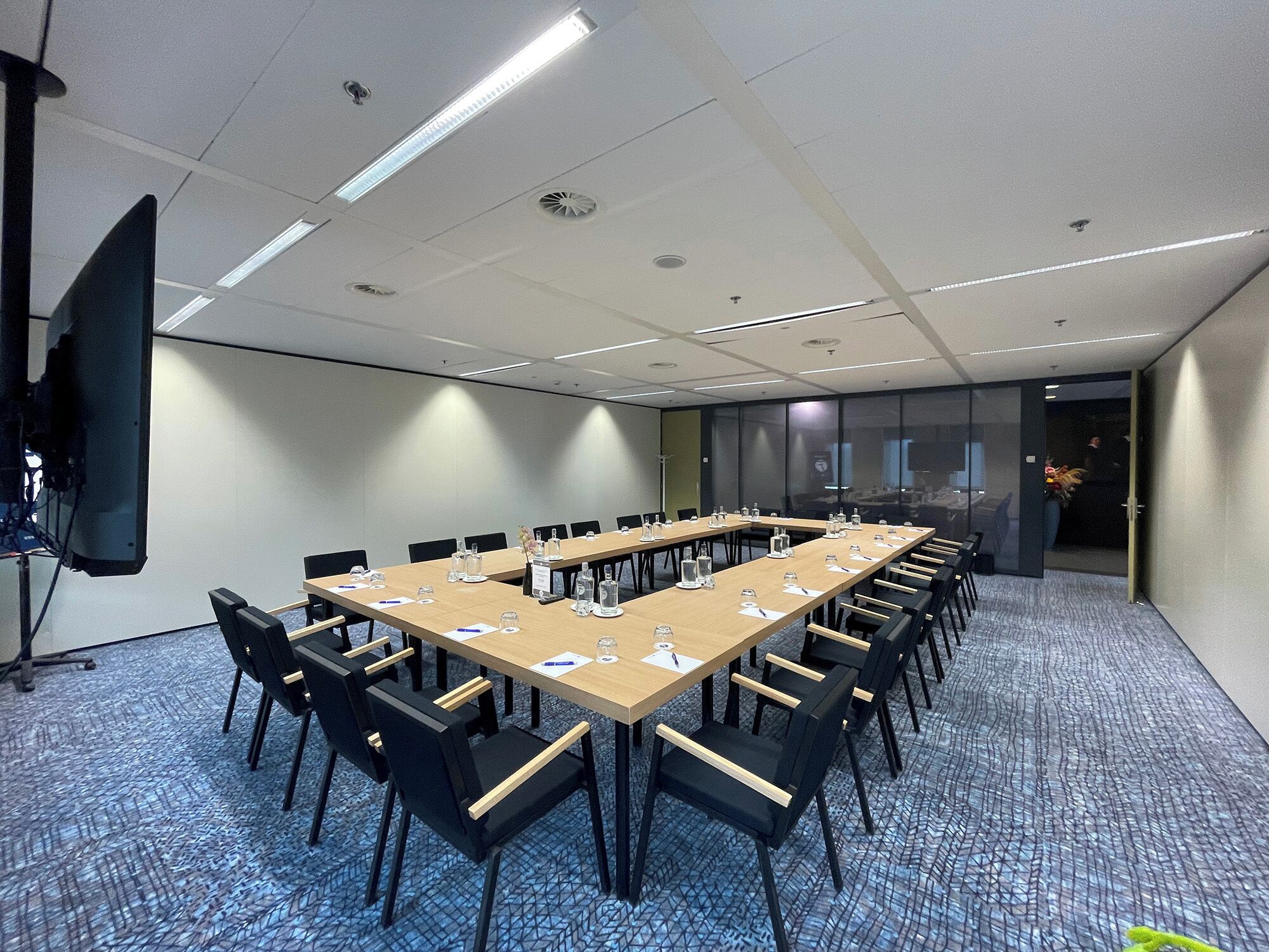 A conference room with a long table, chairs, and a projector screen.