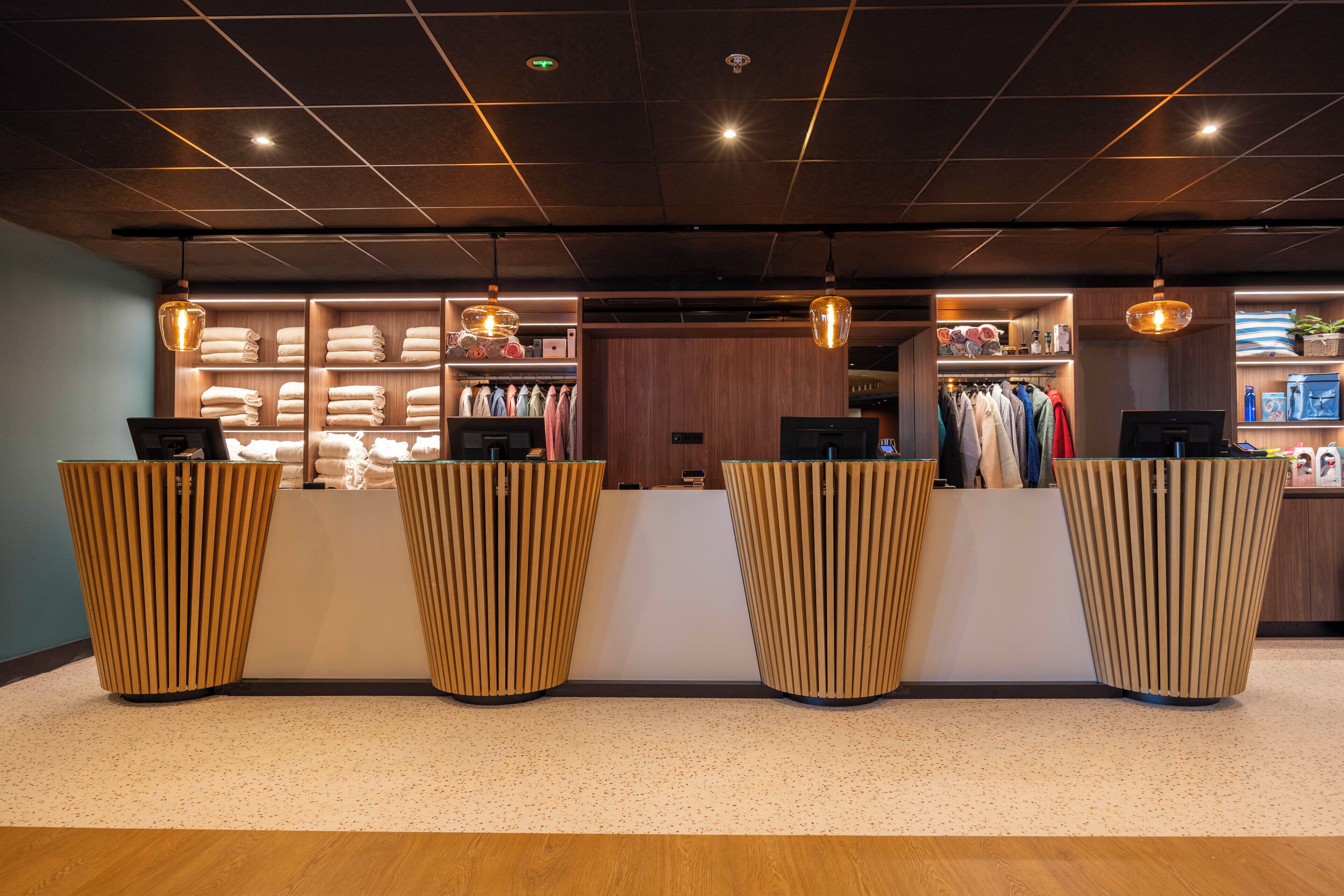 A reception area with a wooden reception desk, a clothing rack, and a shelf with towels.