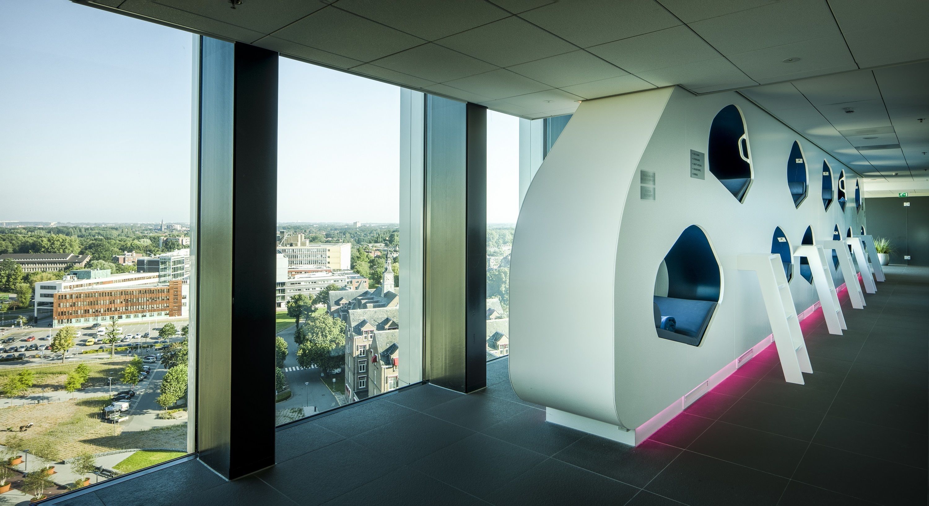Un interior moderno con grandes ventanales que ofrecen vistas a la ciudad, un diseño arquitectónico único con formas circulares y una estética limpia y minimalista.