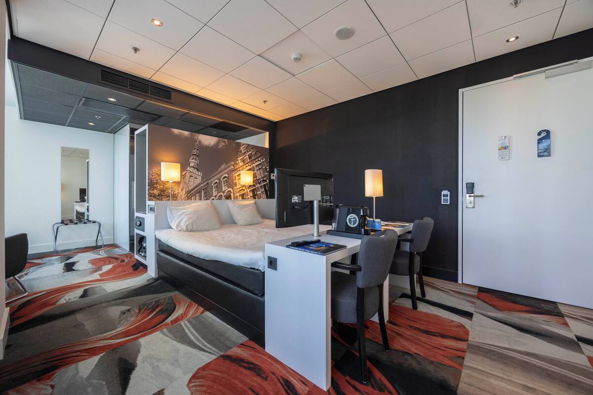 Ein Hotelzimmer mit Bett, Schreibtisch, Stuhl und einem großen Fenster.