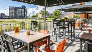 Un patio al aire libre con mesas y sillas, sombrillas y vistas a un paisaje urbano.