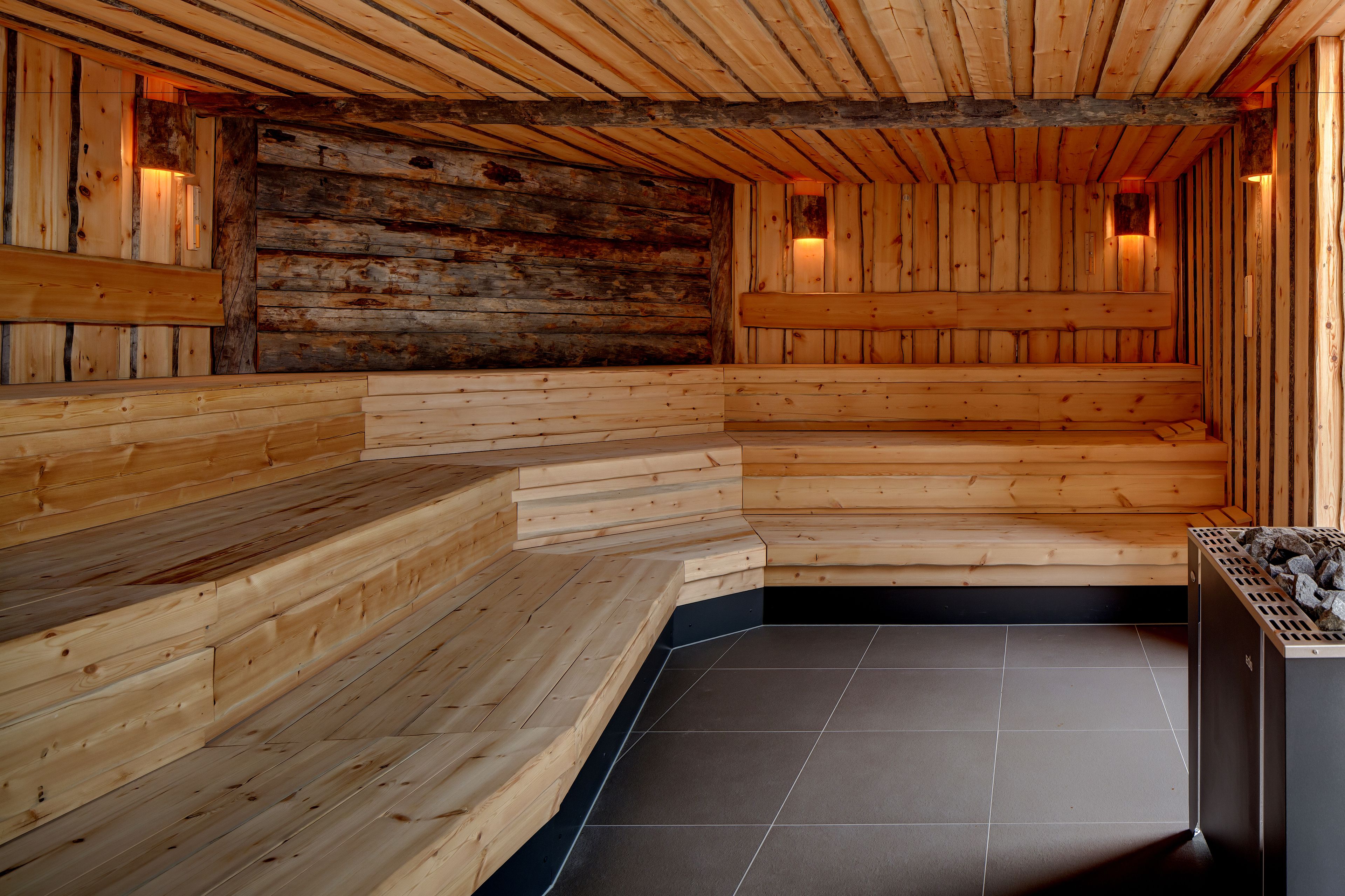 A wooden sauna with tiered benches and a tiled floor.