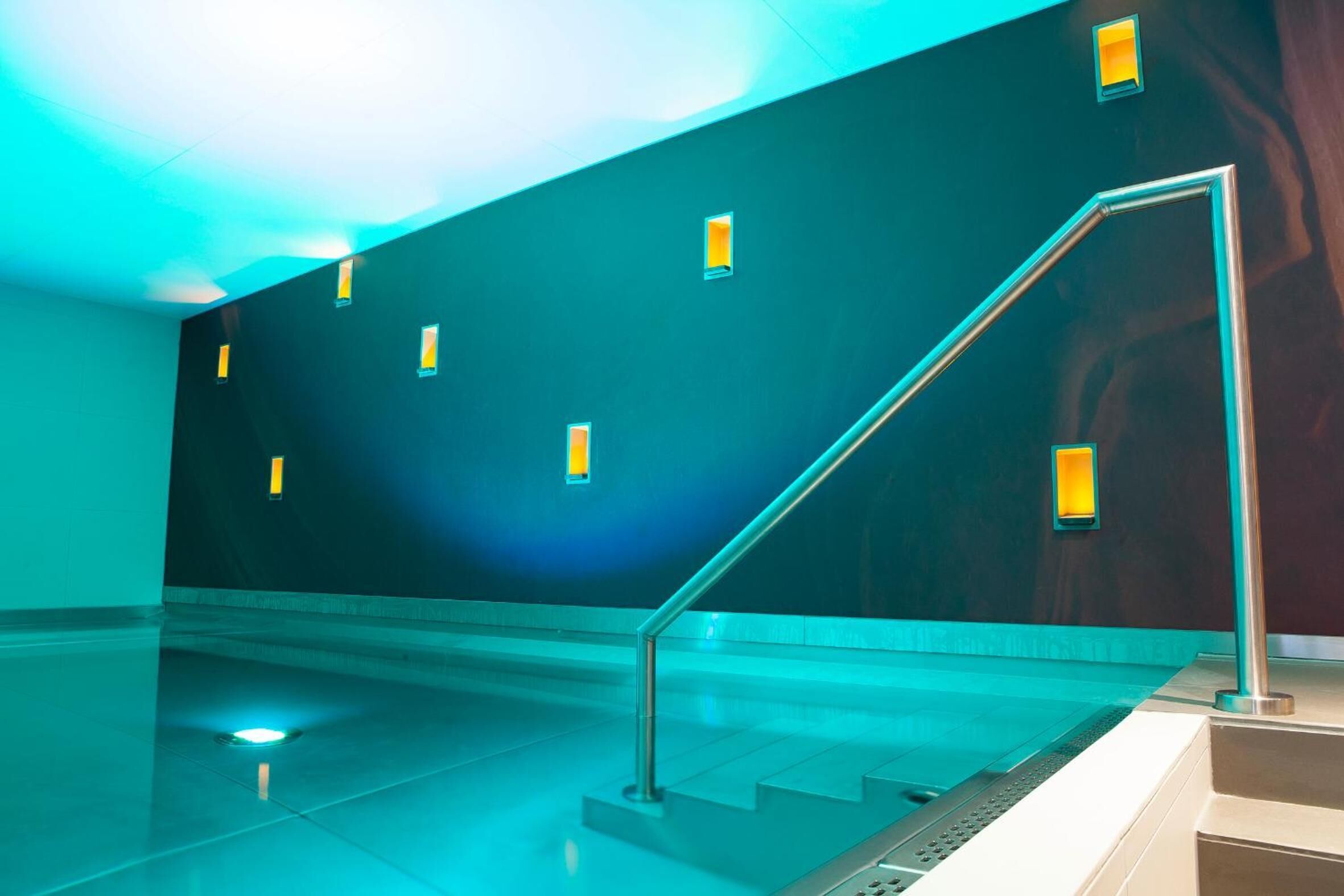 A modern interior with a staircase, recessed lighting, and a polished floor.