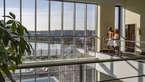 Una habitación de hotel moderna con un amplio ventanal con vistas a una piscina y un lago.