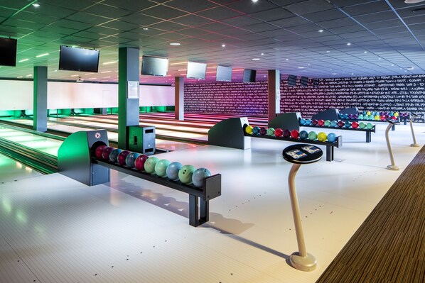 A bowling alley with multiple lanes, bowling balls, and a scoreboard. - Fletcher Wellness - Hotel Helmond (Helmond)