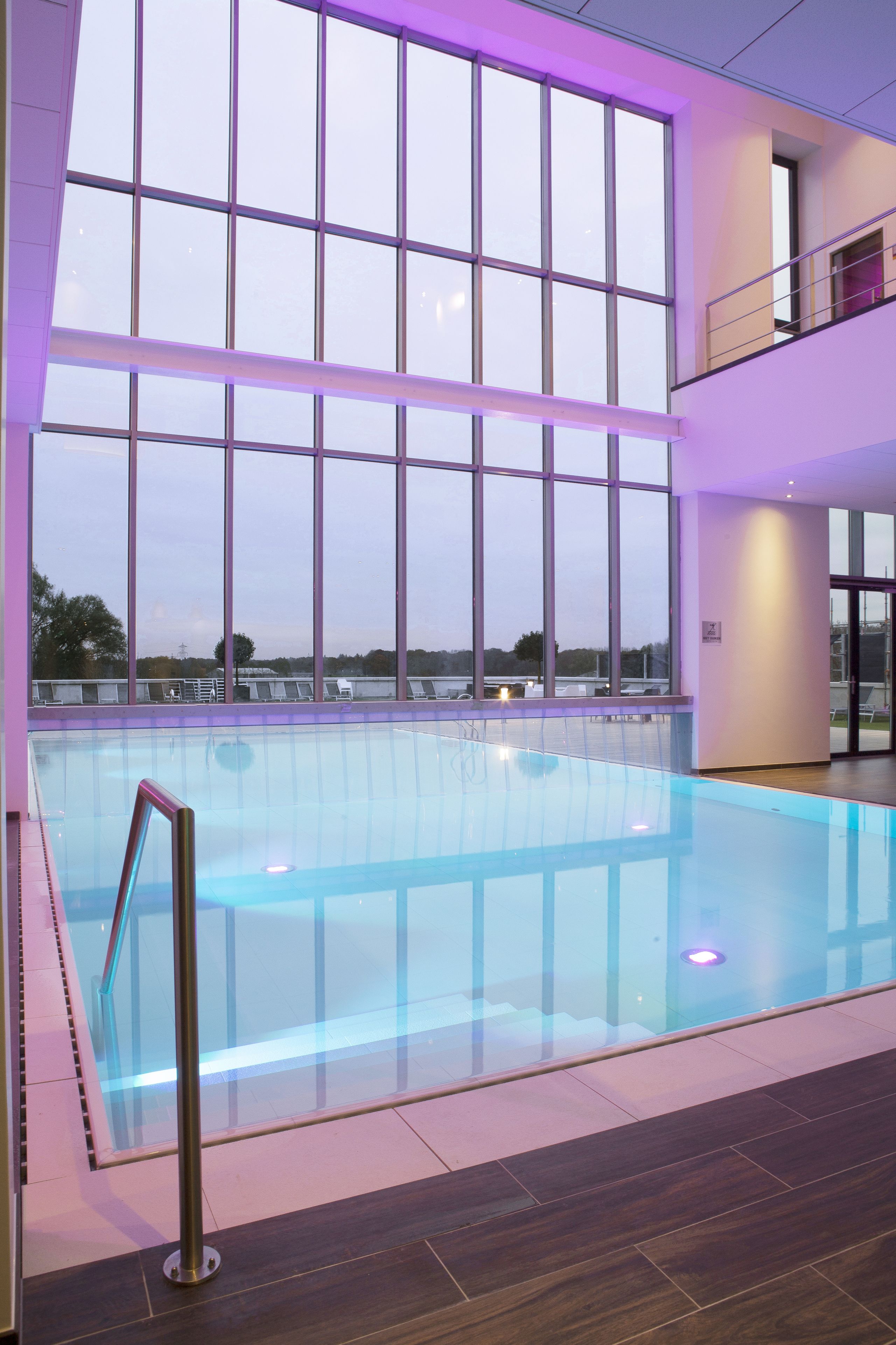 Una piscina interior con grandes ventanales y vistas al cielo.