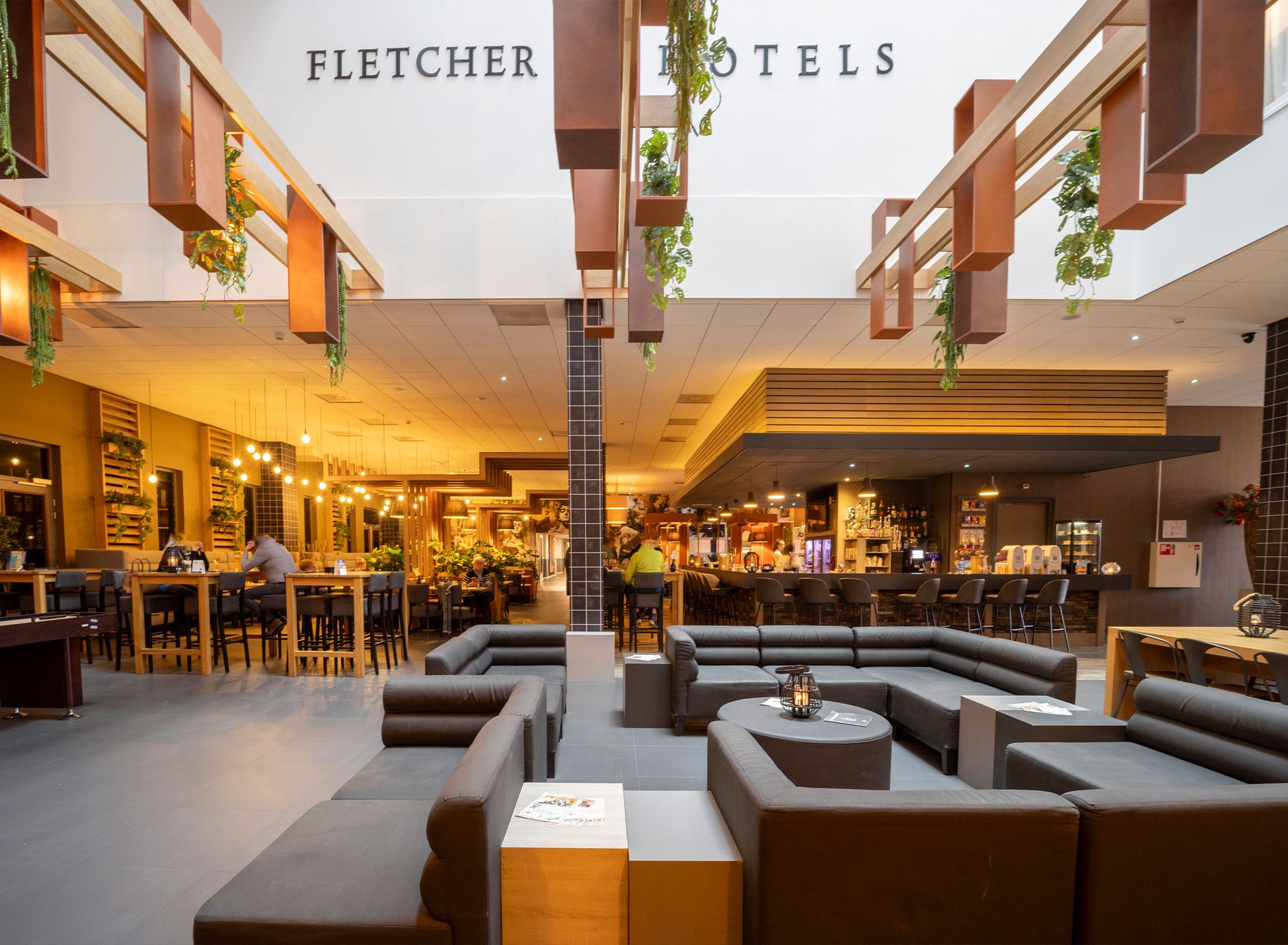Een hotel lobby met zithoeken, een bar en een trap.