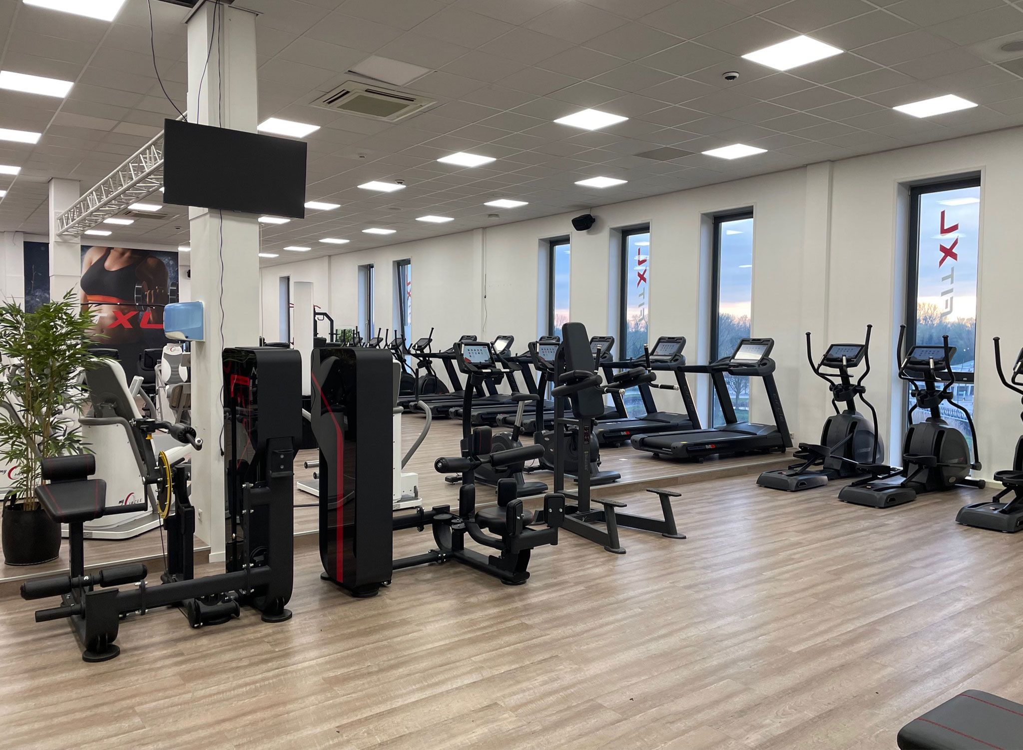 Une salle de sport équipée de tapis de course, d’appareils de musculation et d’un grand miroir.