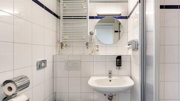 Ein modernes Badezimmer mit einem weißen Waschbecken, einem Spiegel, einem Handtuchhalter und einer Toilette.