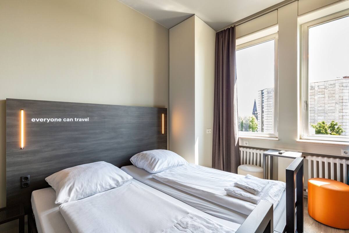 Habitación de hotel con cama, escritorio y ventana con cortinas.