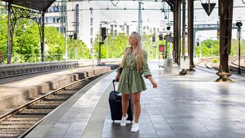 Een vrouw met een koffer op een perron van een treinstation.