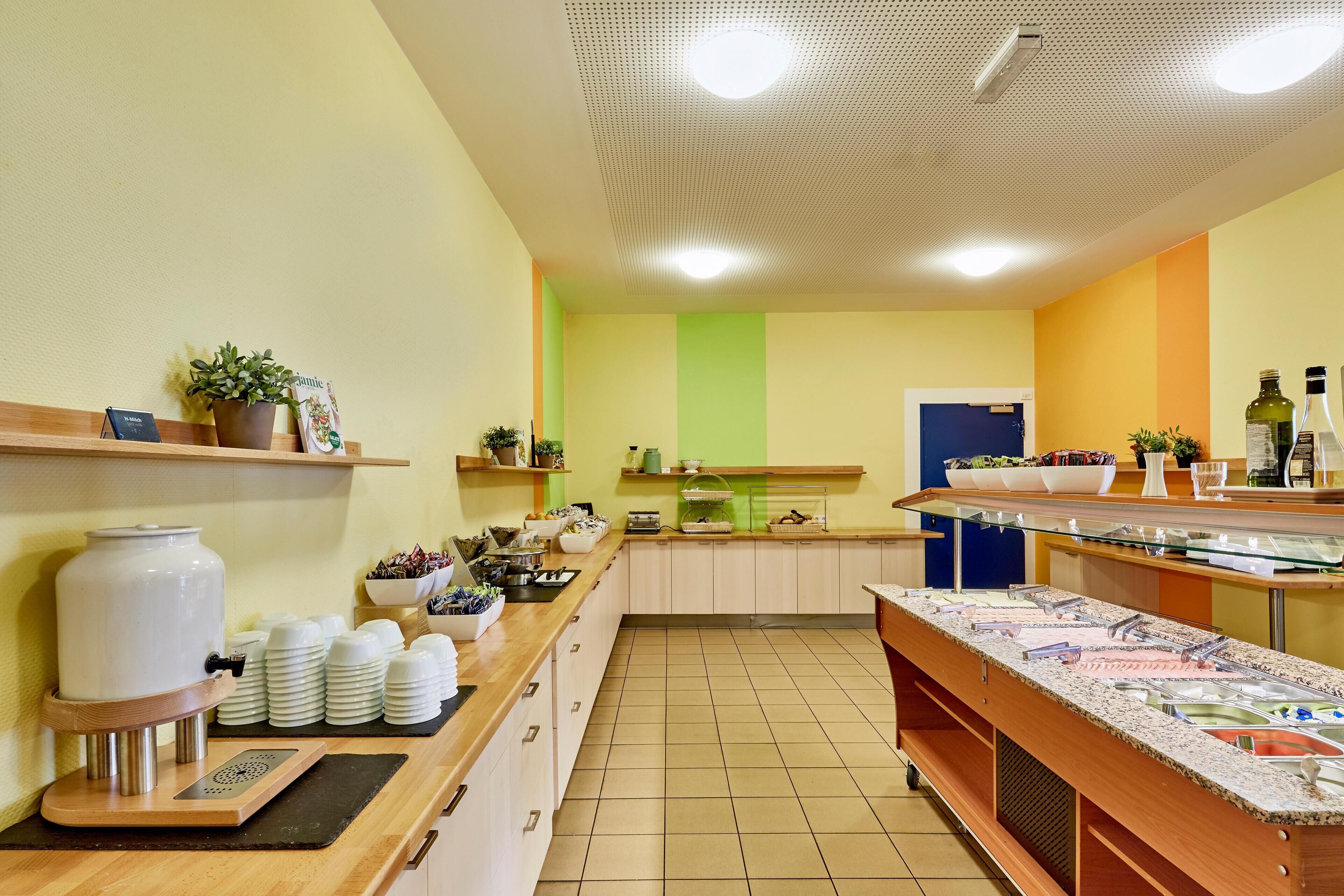 A kitchen area with a buffet setup, including a coffee station, various food containers, and a sink.